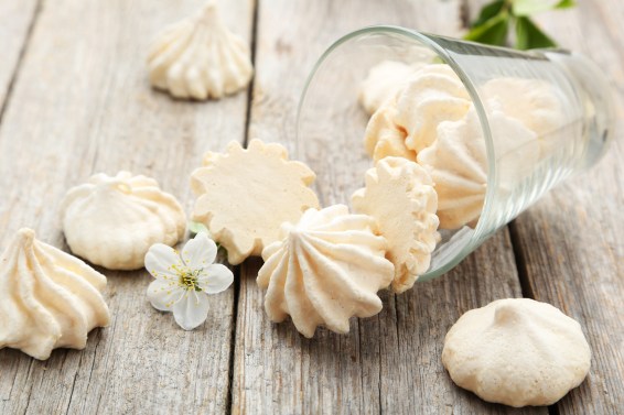 French meringue cookies with glass on grey wooden background
